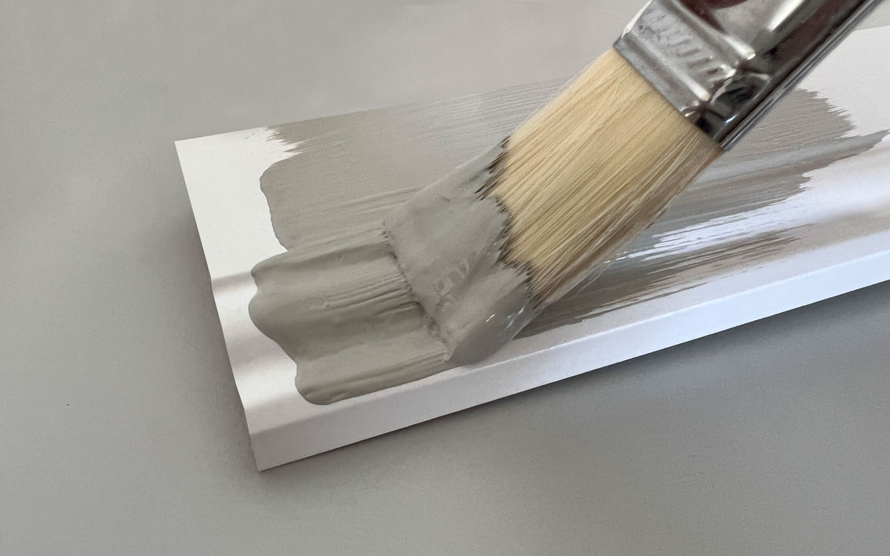 Sockelleiste wird mit einem Pinsel und grauer Farbe sauber überstrichen.