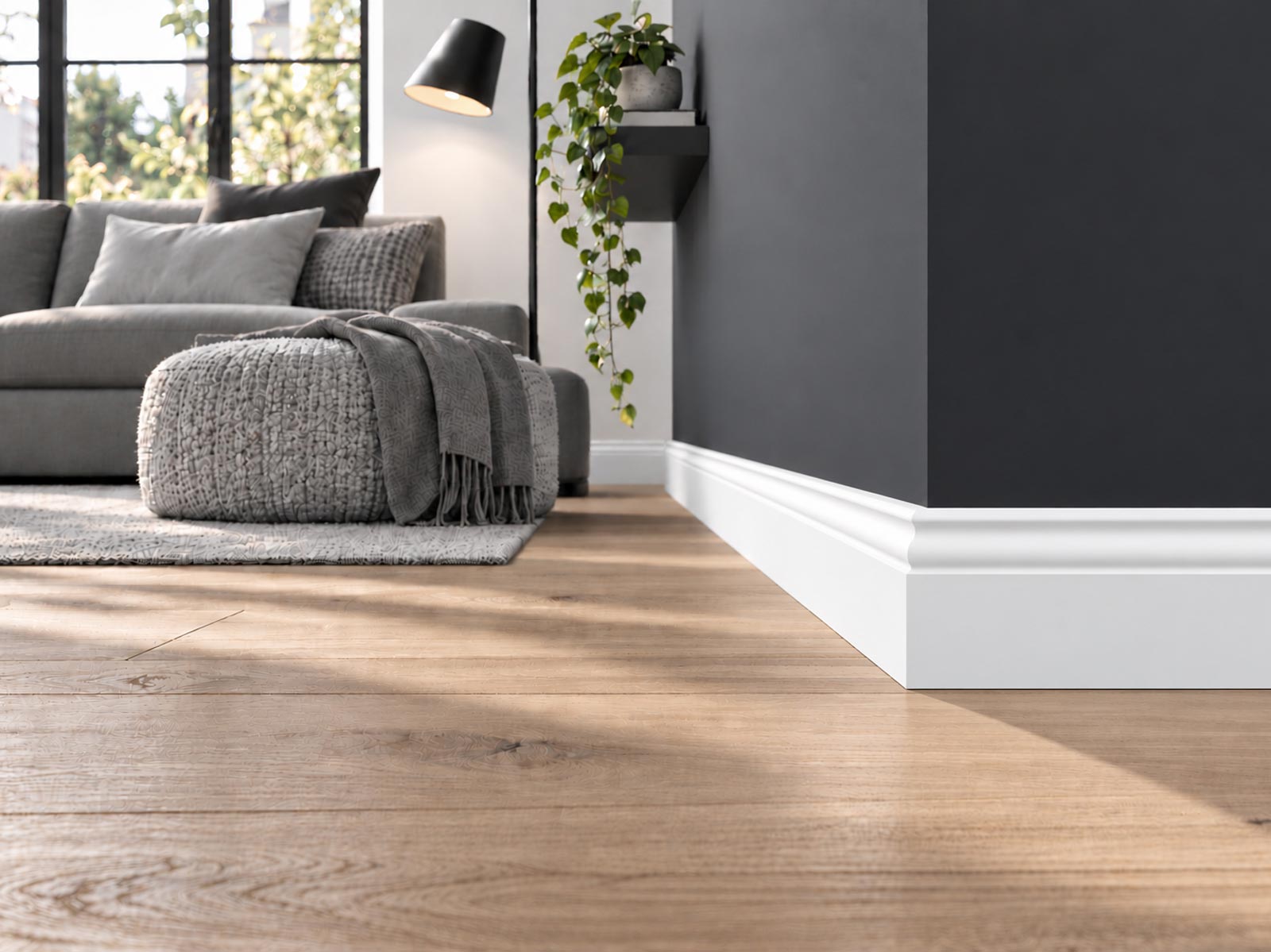 Wohnzimmer mit Holzdielenboden und dunkelgrauer Wand, weiße Hamburger Leiste Pro RAL9016 mit 95 mm am Wandabschluss