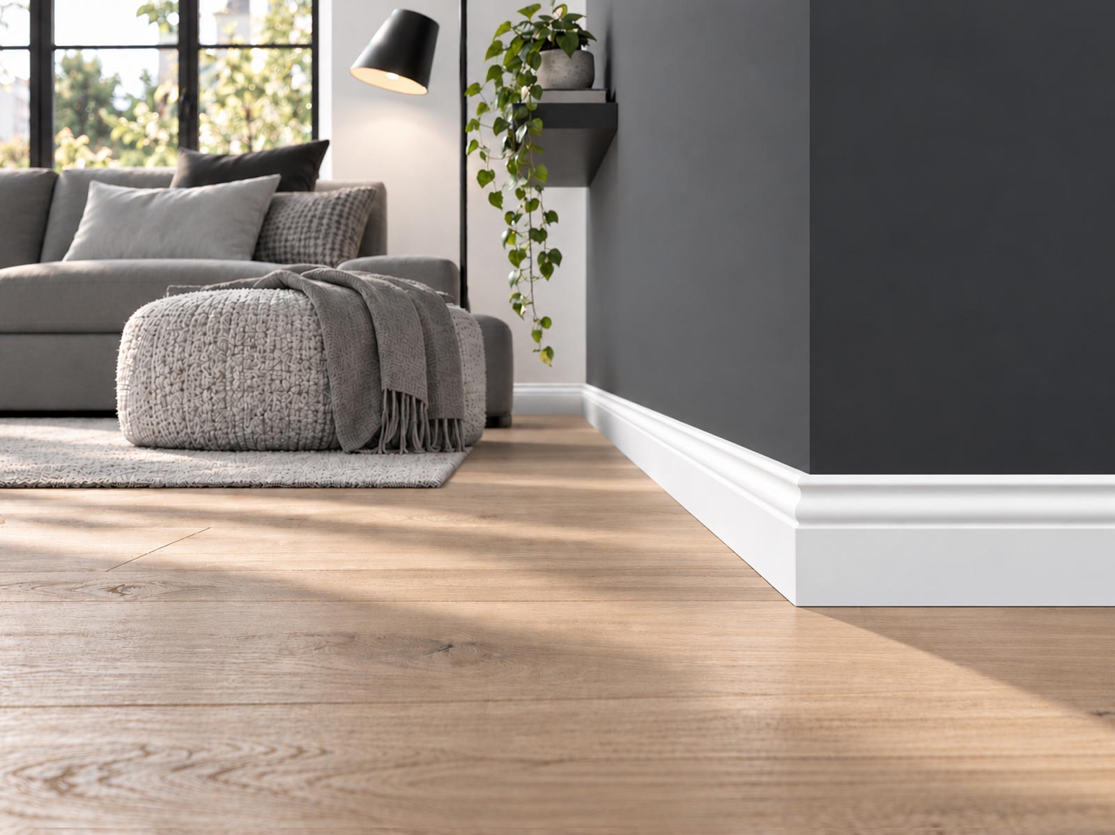 Wohnzimmer mit Holzdielenboden und dunkelgrauer Wand, weiße Hamburger Leiste Pro RAL9016 mit 58 mm am Wandabschluss